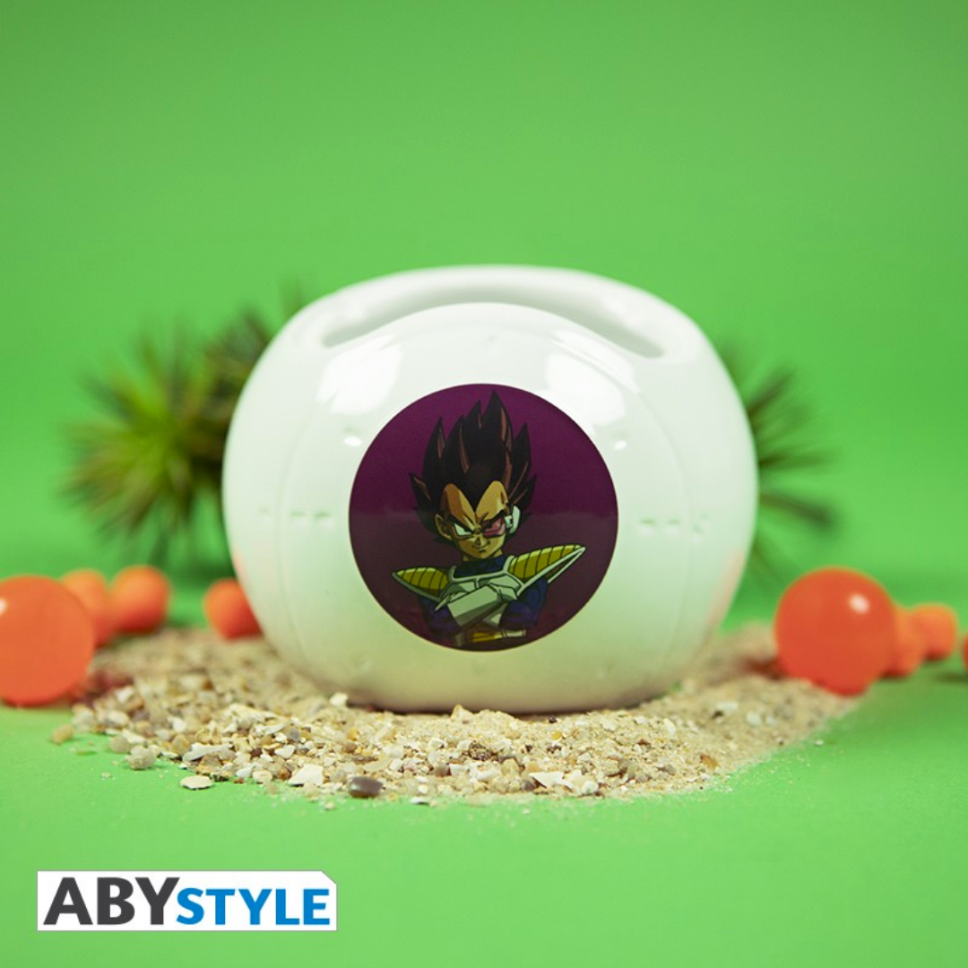 ABYstyle Dragon Ball Z Vegeta space pod mug displayed on sand with Dragon Balls and palm tree, perfect for anime collectors.