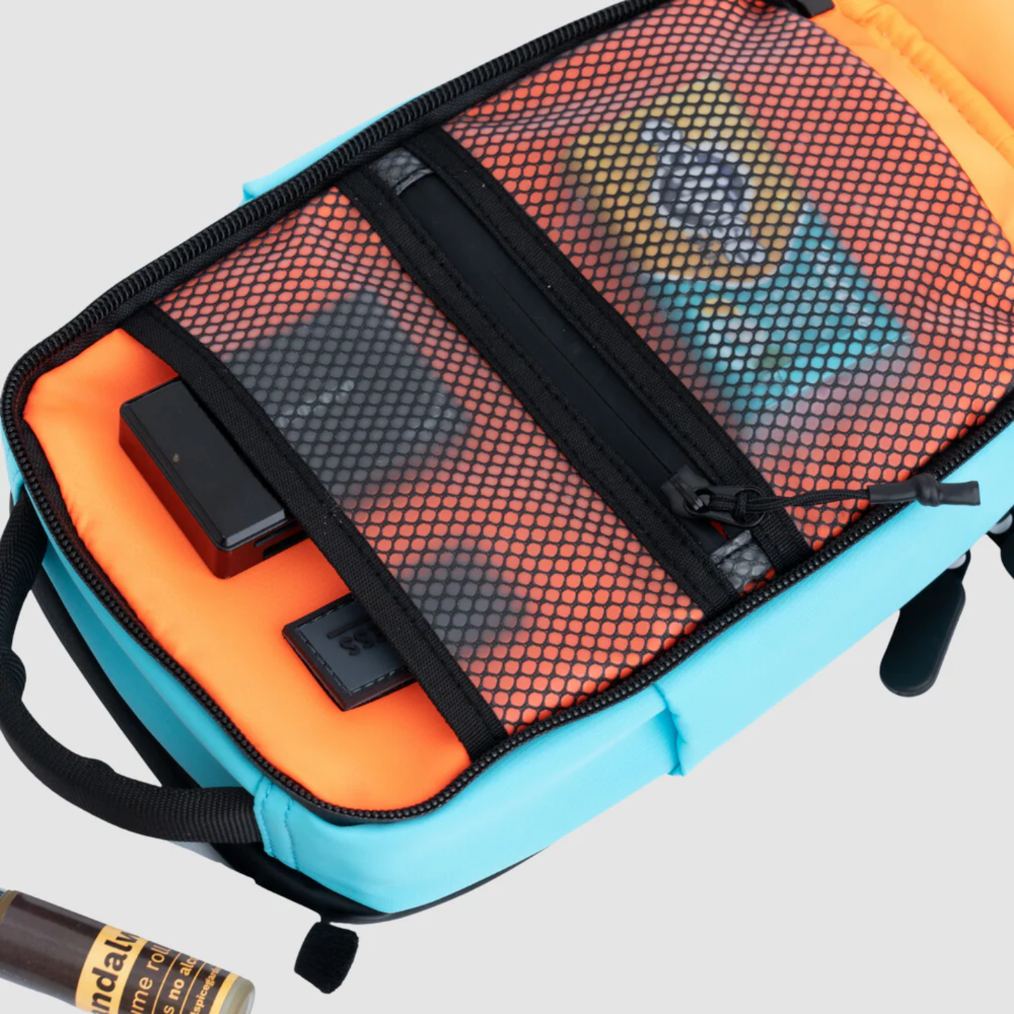 Bold Mimic Sling Bag in turquoise, open view showing mesh pocket organizer with tech gadgets and essentials; smart, versatile interior storage design.