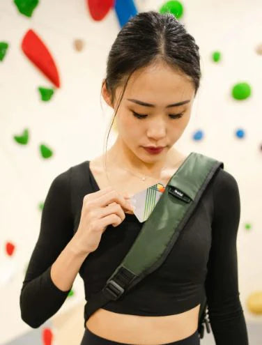 Bold Quiver army green bag strap with front card slot, worn crossbody by woman in black top, ergonomic design for secure and convenient access