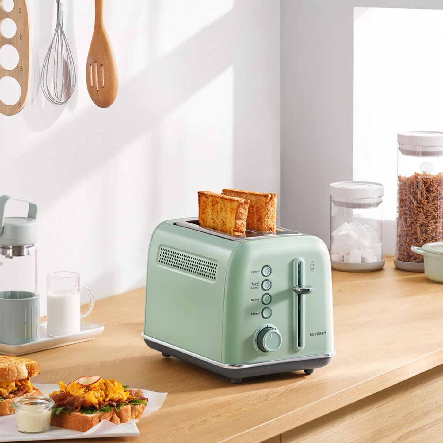 Buydeem 2-Slice Toaster Cozy Greenish with golden toast on kitchen counter, next to breakfast sandwiches, milk, and cereal jars