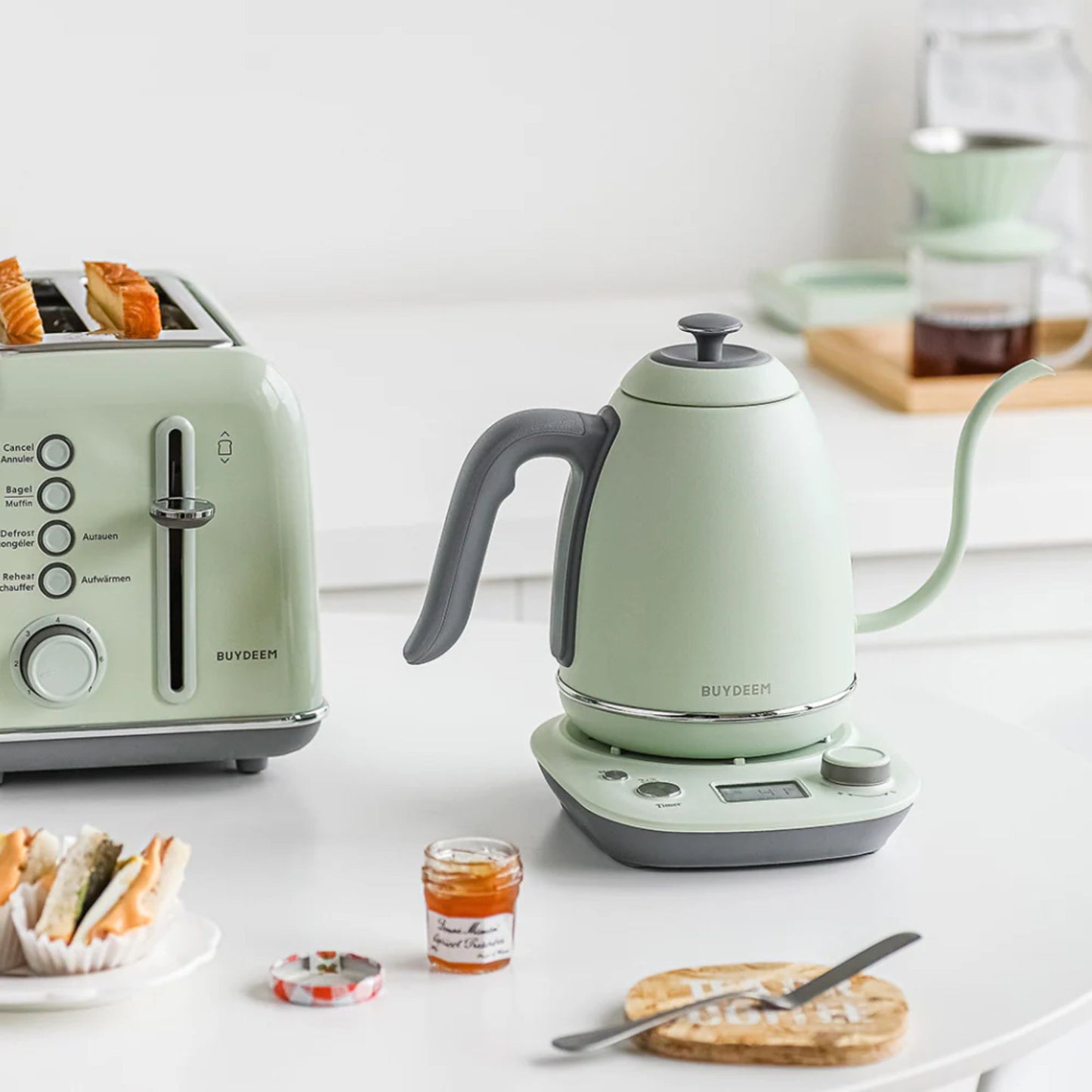 Buydeem mint green electric kettle and toaster on white kitchen counter, stylish breakfast setup with coffee, pastry, and jam in a bright modern home