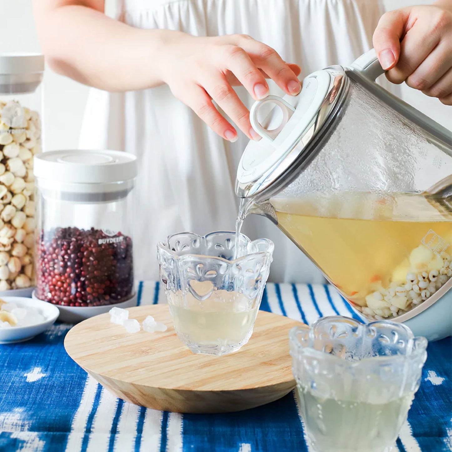 Pouring hot soup or tea from Buydeem Multi-Functional 4-in-1 Health Pot glass kettle into decorative cup, healthy beverage prep in kitchen