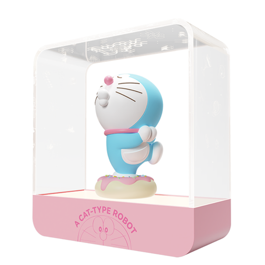 Doraemon Starry Night Light featuring a 3D Doraemon figure with pink nose and collar, standing on a donut-shaped base inside a transparent rectangular lamp with a pink base labeled "A Cat-Type Robot.