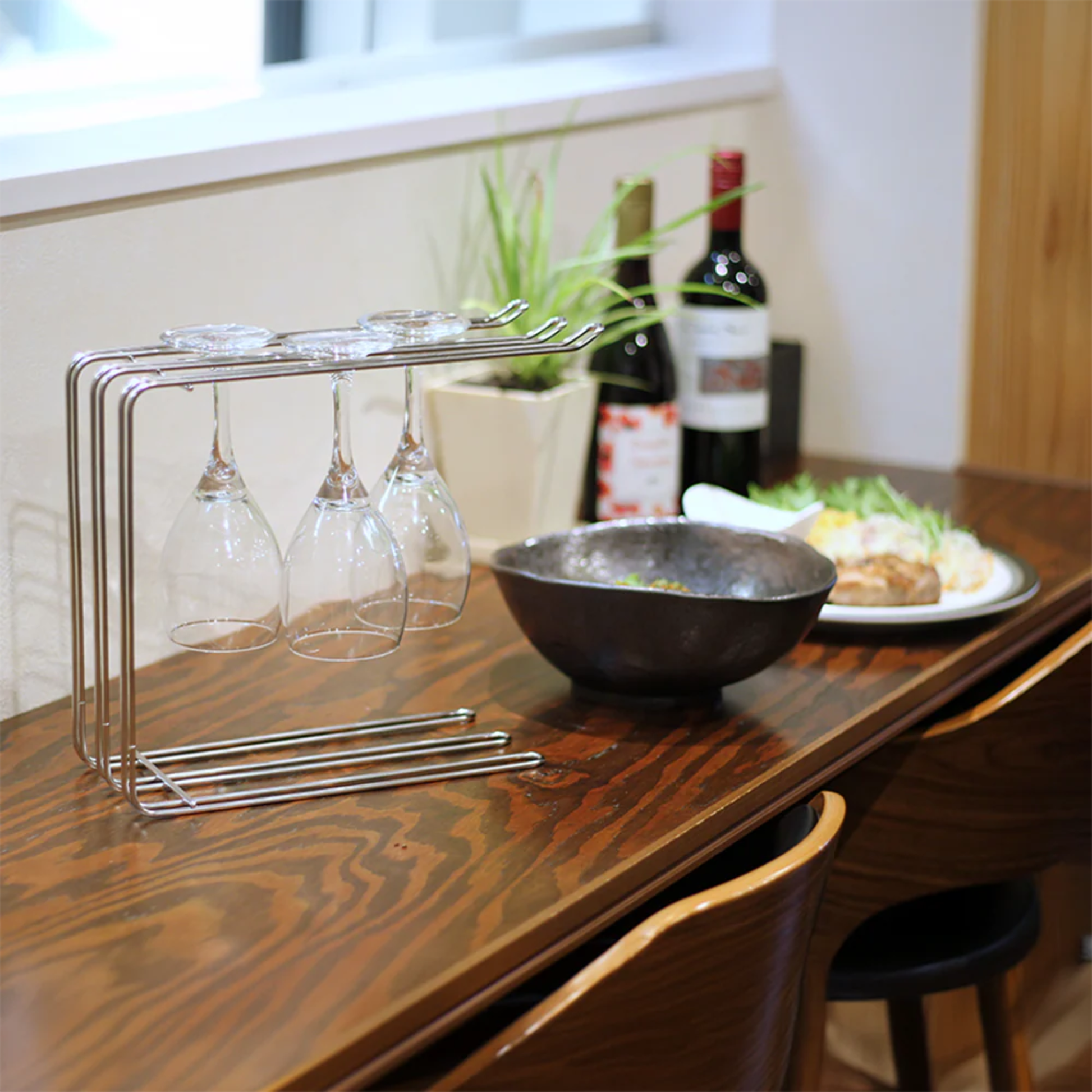 Hanauta stainless steel kitchen rack hanger on a dining table, used for drying wine glasses, stylish kitchen organiser for modern home decor.