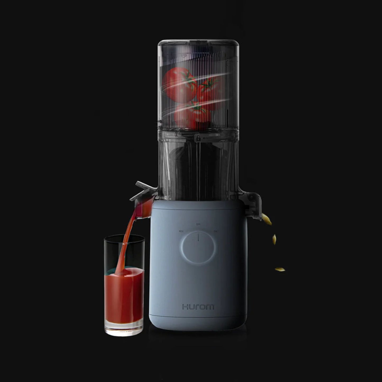 Hurom H310A Slow Juicer light blue model, compact BPA-free juicer making fresh tomato juice, action shot with glass and dark background