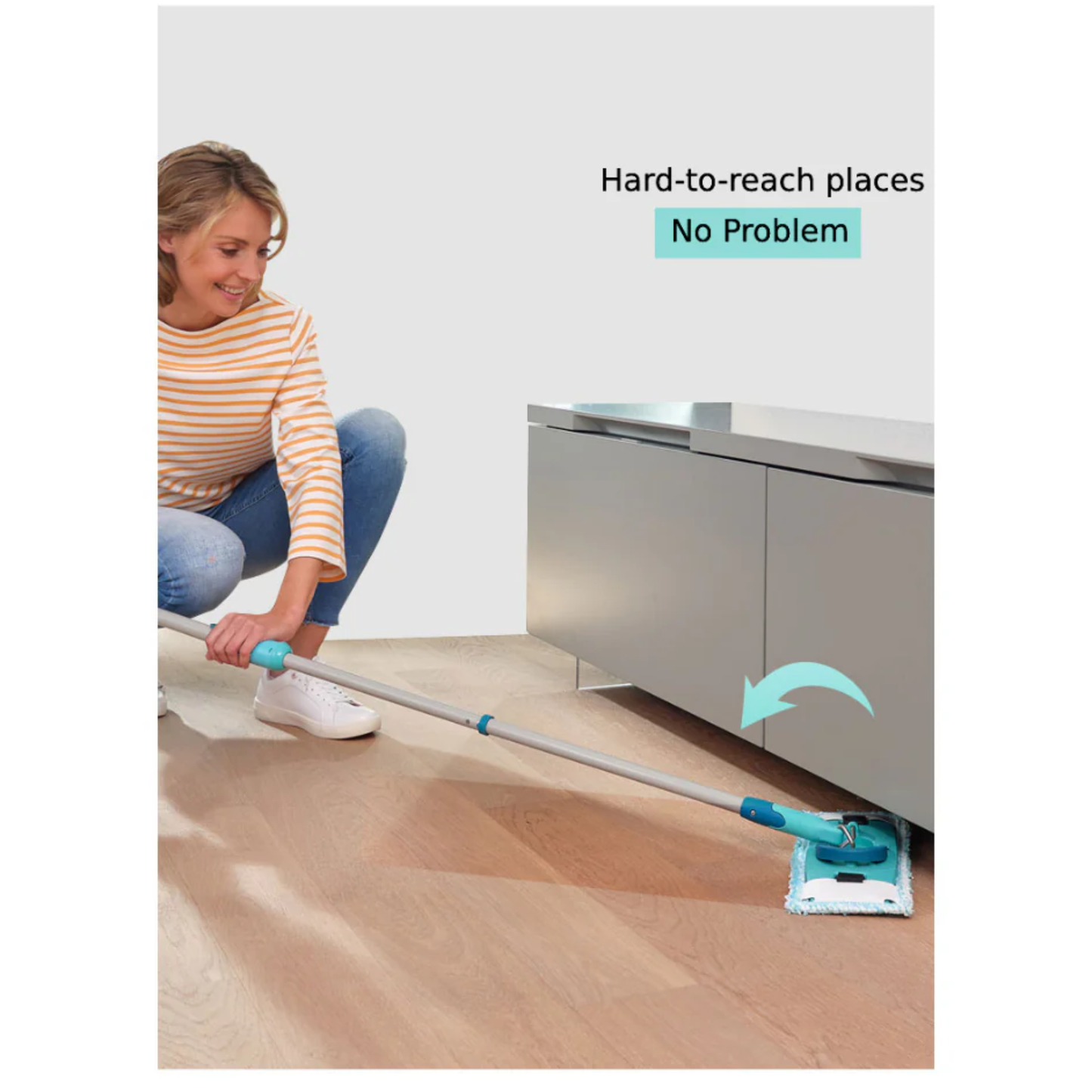 Person cleaning under low cabinet with Leifheit Clean Twist Ergo flat mop, using 360 degree joint to reach hard-to-access areas on wooden floor.