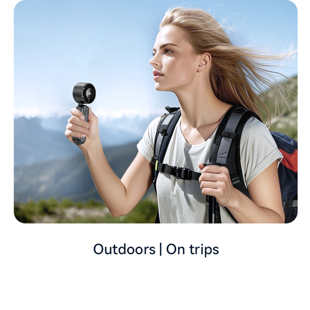 USAMS ZB352 black folding handheld fan used outdoors and on trips, shown with hiker in scenic mountain background