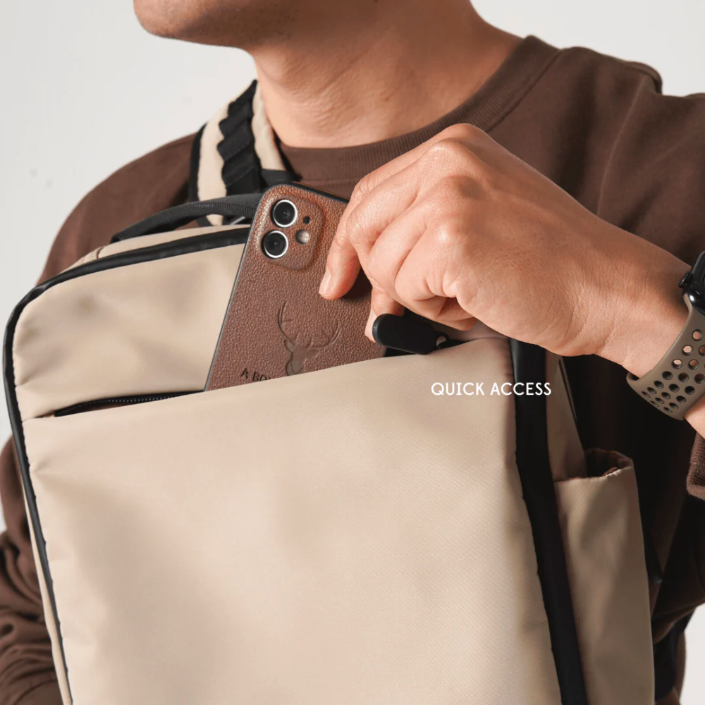 Man accessing smartphone from quick access front pocket of Bold beige crossbody sling bag with black trim, convenient design for travel and daily use