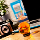 ABYstyle Dragon Ball Z 4 stars Dragon Ball acrylic replica on display base, shown on a wooden desk with a laptop, camera, and plant in a lifestyle workspace setting.