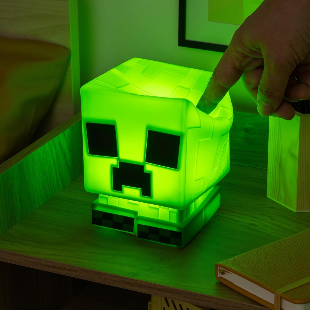 A hand squishing the soft silicone texture of the Minecraft Creeper SquishyGlo light.