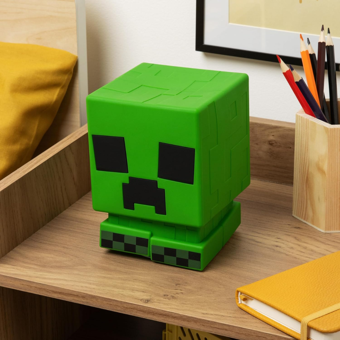 A hand squishing the soft silicone texture of the Minecraft Creeper SquishyGlo light.