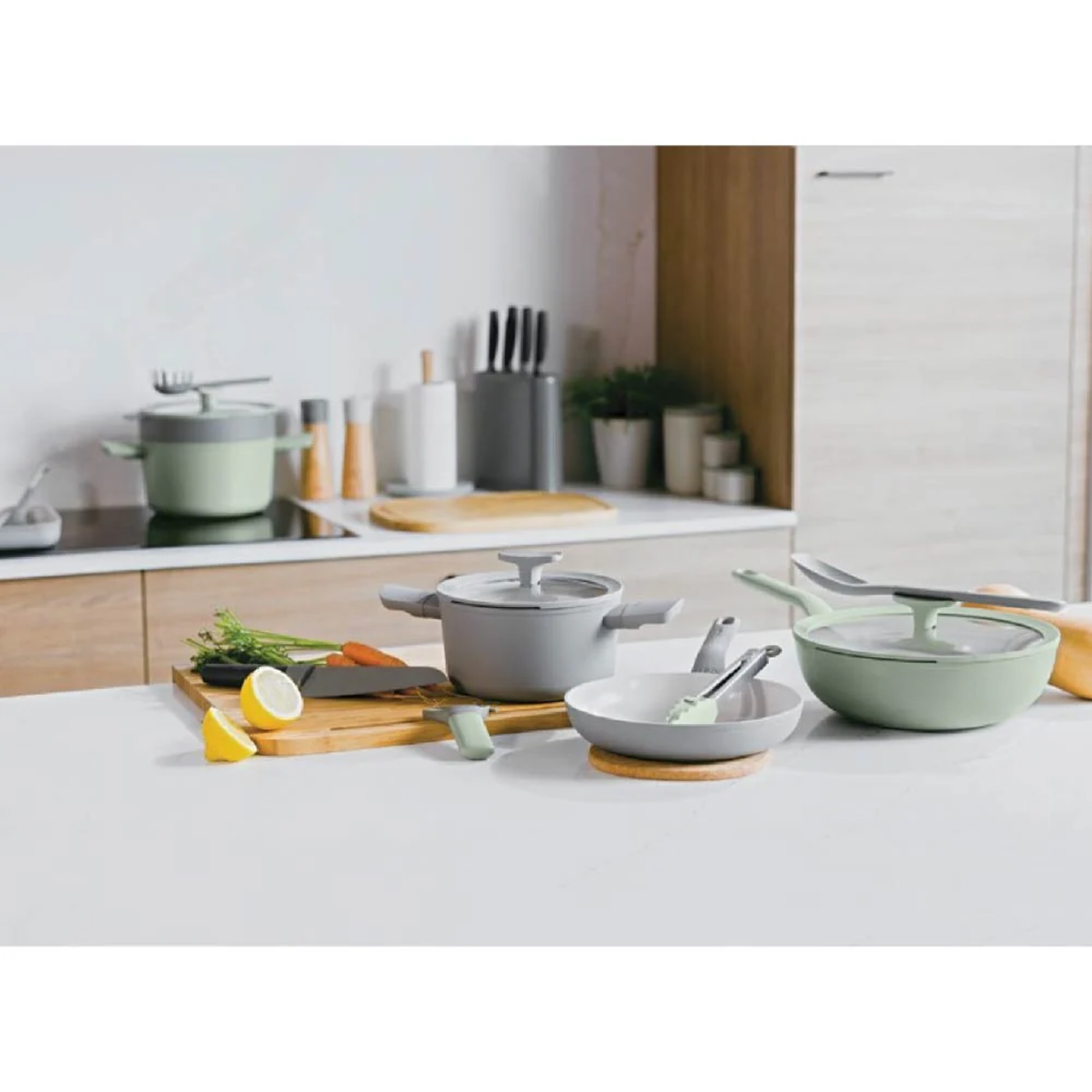 Modern kitchen with BergHOFF Balance sage and grey non-stick cookware set, including covered casserole and frying pan with utensils on countertop.