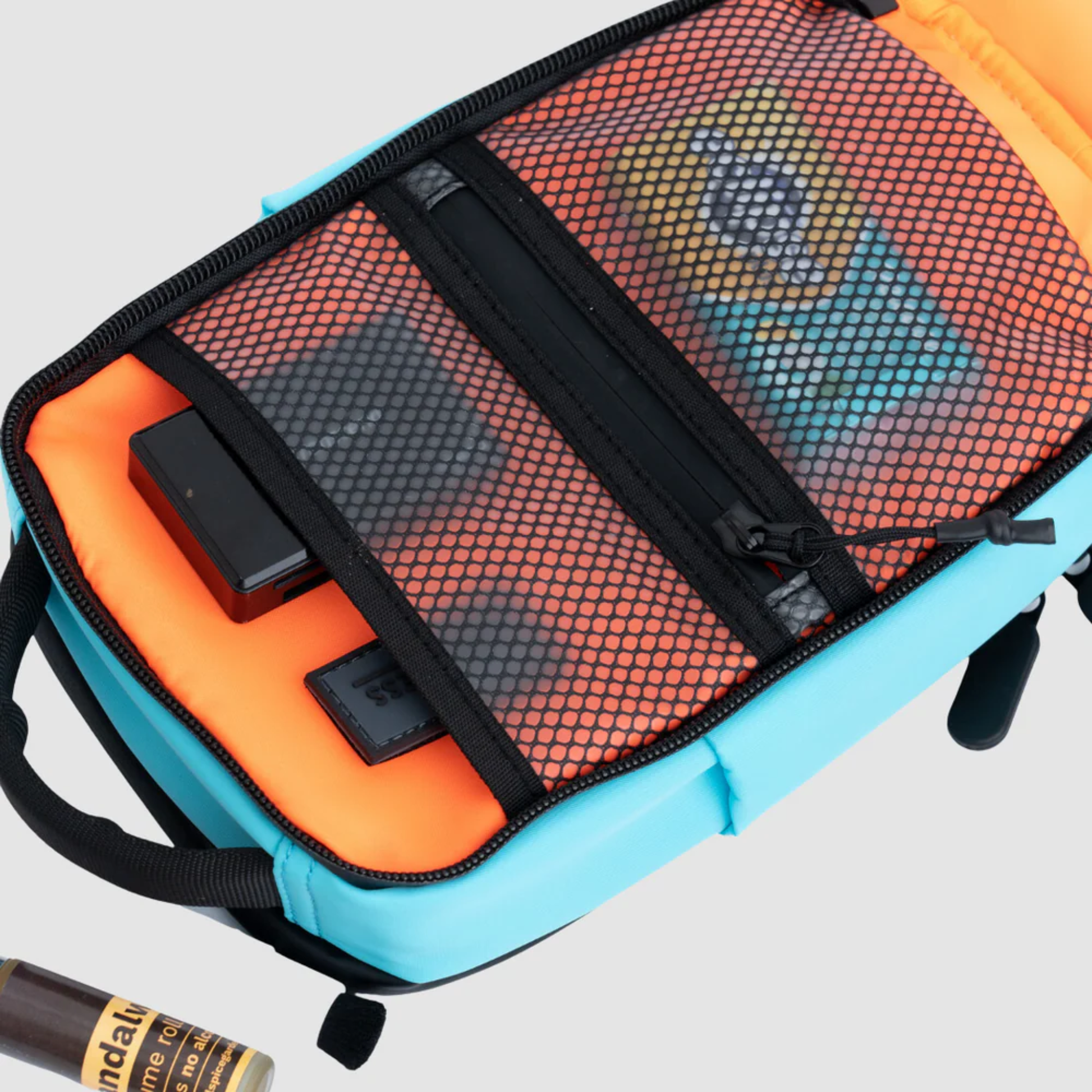 Bold Mimic Sling Bag in turquoise, open view showing mesh pocket organizer with tech gadgets and essentials; smart, versatile interior storage design.