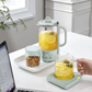 Buydeem Mini Health Pot Kettle Cooker on office desk brewing lemon tea, ideal for workspace or home use