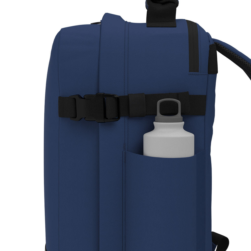 CabinZero Classic Tech Bag 28L in Navy Blue featuring a side water bottle pocket and adjustable compression strap for organized hydration and practical travel or commute use