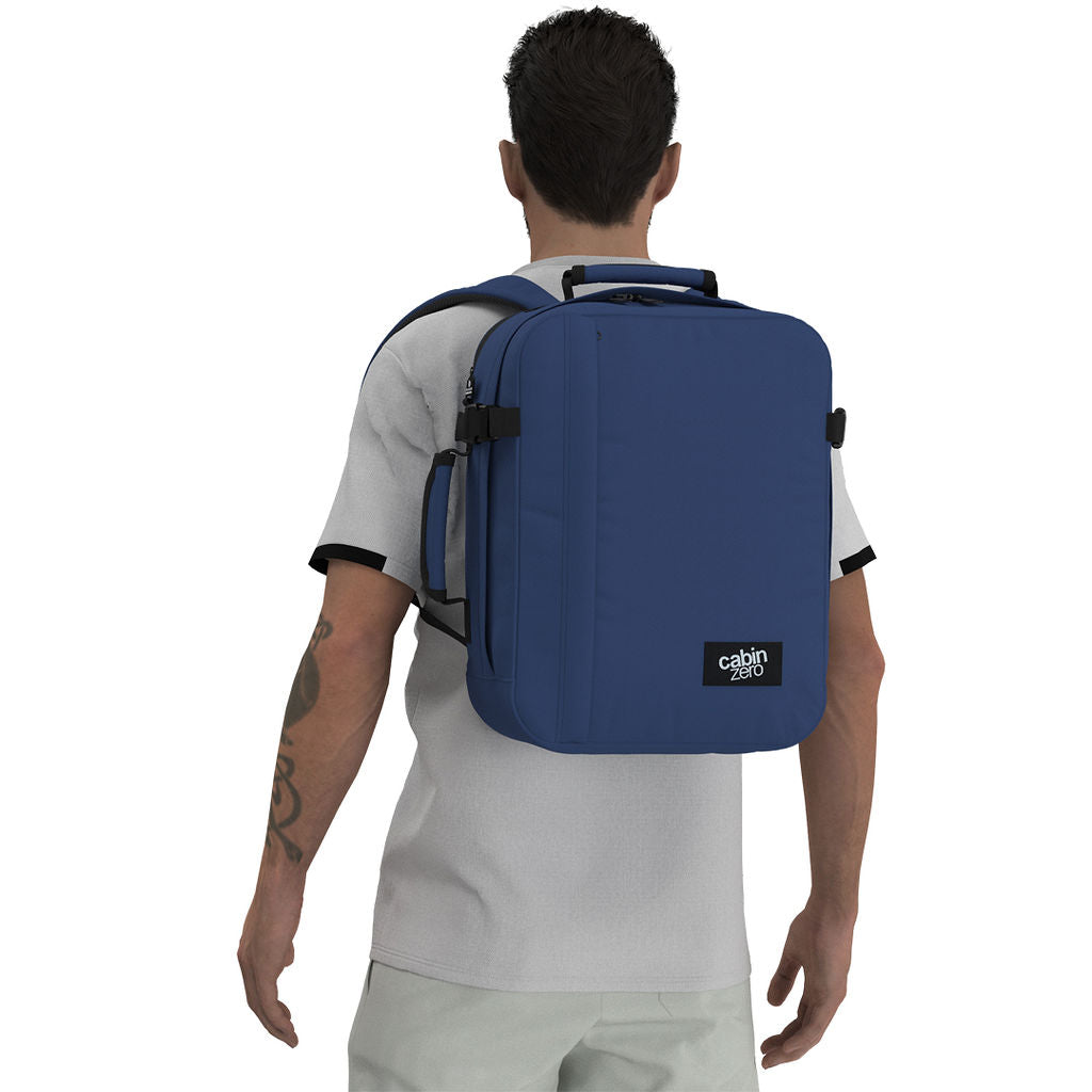 Man wearing CabinZero Classic Tech Bag 28L in Navy Blue, showcasing ergonomic shoulder straps and minimalist design—perfect for tech-savvy travelers and daily commuters