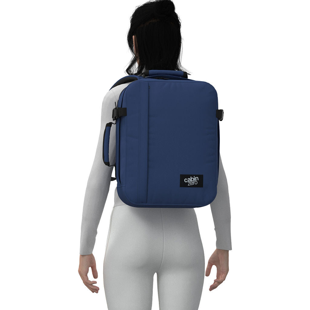 Woman wearing CabinZero Classic Tech Bag 28L in Navy Blue, highlighting padded shoulder straps and ergonomic fit—ideal backpack for stylish commuters, travelers, and daily tech organization