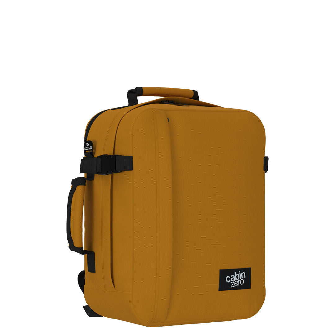 Angled view of CabinZero Classic Tech Bag 28L in Orange Chill featuring compression strap, side handle, and padded back—perfect for tech essentials, daily commutes, and travel adventures.