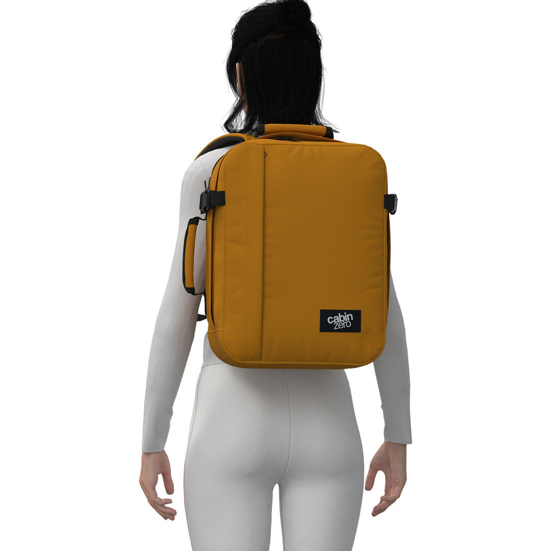 Woman wearing CabinZero Classic Tech Bag 28L in Orange Chill, highlighting padded shoulder straps and ergonomic fit—ideal for stylish tech commuters, travel, and everyday organization.
