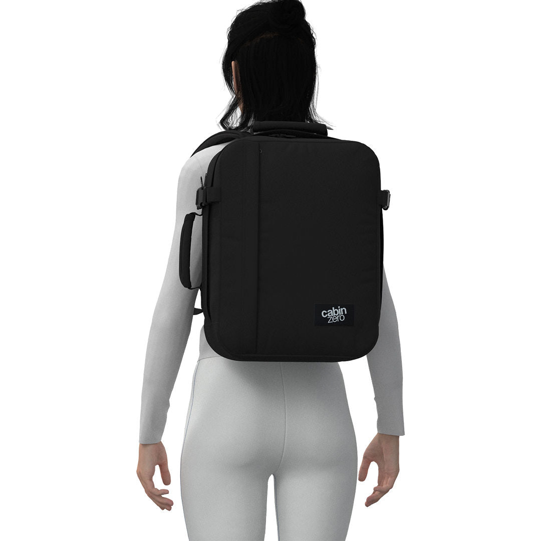 Woman wearing CabinZero Classic Tech Bag 28L in Absolute Black, showcasing ergonomic design and padded straps—ideal backpack for travel, work, and everyday commuting.