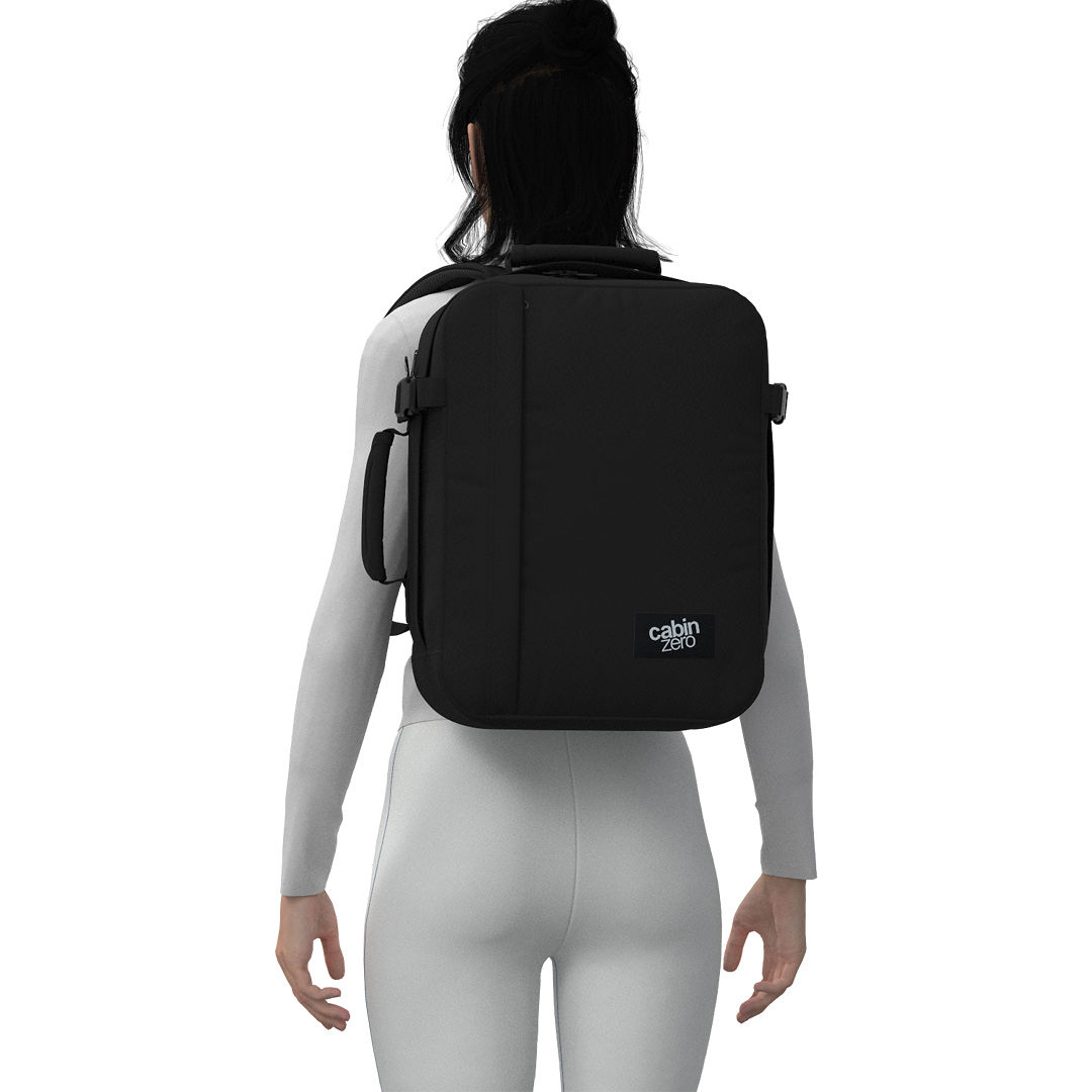 Woman wearing CabinZero Classic Tech Bag 28L in Absolute Black—lightweight travel backpack with laptop sleeve, ideal for commuting, tech gear, and everyday use