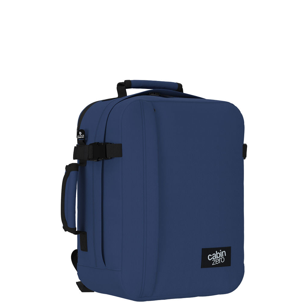 Angled view of CabinZero Classic Tech Bag 28L in Navy Blue featuring compression straps, side handle, and minimalist design—ideal backpack for business travel, commuting, and tech organization.