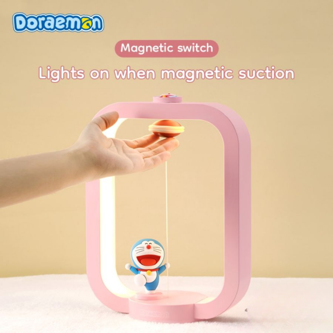 Hand activating pink Doraemon Dorayaki magnetic night light with magnetic switch, featuring smiling Doraemon figure and floating dorayaki, on beige background.