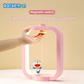 Hand activating pink Doraemon Dorayaki magnetic night light with magnetic switch, featuring smiling Doraemon figure and floating dorayaki, on beige background.
