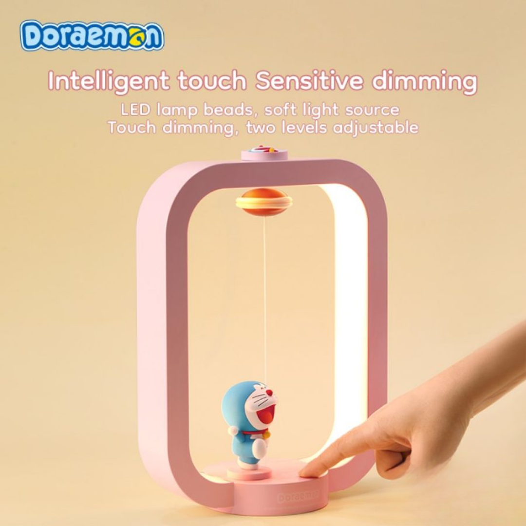 Hand touching the base of a pink Doraemon Dorayaki magnetic night light with intelligent touch-sensitive dimming, featuring a soft LED light and smiling Doraemon figure inside a modern frame.