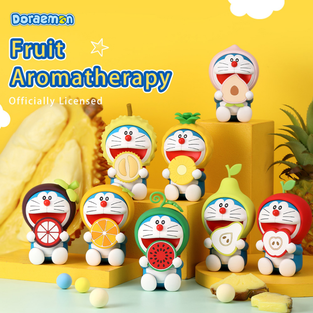 Collection of Doraemon Fruit Aromatherapy diffusers, each featuring a smiling Doraemon character dressed in different fruit-themed hoods—peach, durian, pineapple, mangosteen, orange, watermelon, pear, and apple—arranged on yellow platforms with fruit slices and a bright yellow background, "Fruit Aromatherapy Officially Licensed" text above