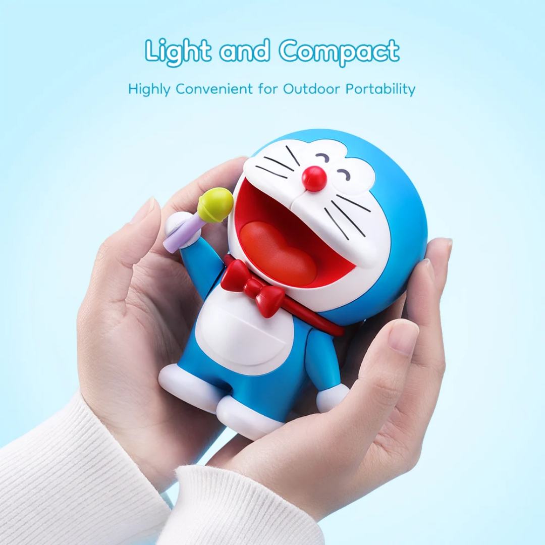 Hands holding a compact Doraemon Mic King Bluetooth Speaker with a red bow tie and green microphone, showcasing its light and portable design on a blue background with "Light and Compact" text