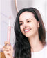 Smiling woman holding a Fairywill pink electric toothbrush in a bathroom setting, demonstrating product use