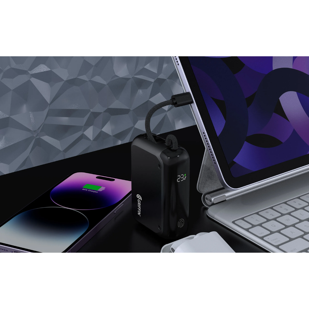 Griffin 10,000mAh power bank with digital battery display, integrated braided USB-C cable charging a tablet, shown alongside a smartphone and keyboard for portable device charging.