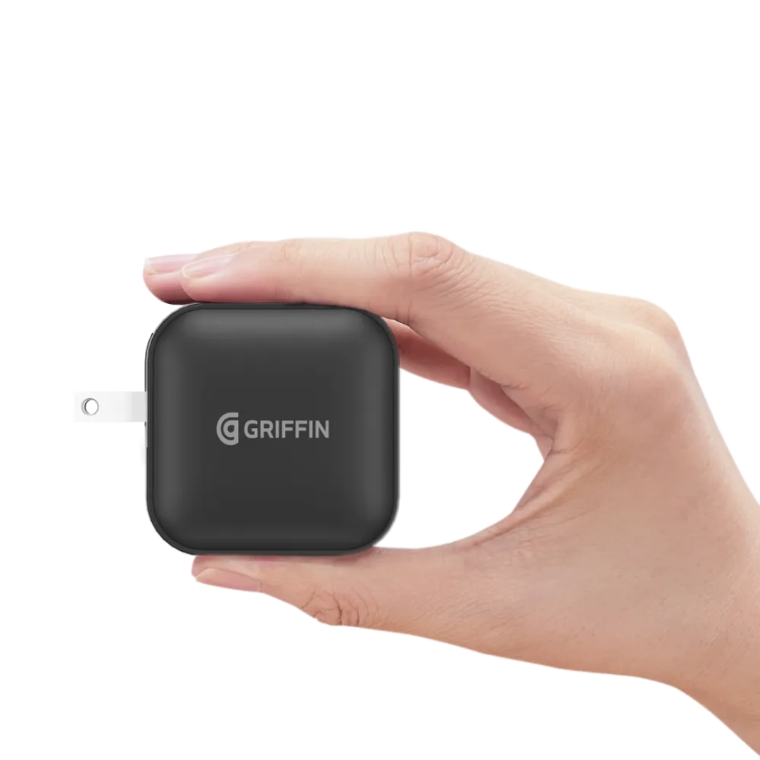 Hand holding a compact Griffin 48W GaN dual USB-C fast charger travel adapter.