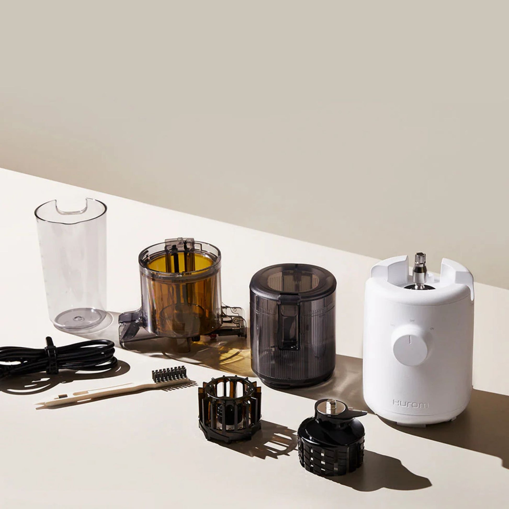 Hurom H310A Slow Juicer white model with all accessories, including chamber, hopper, multi-screw, cleaning brush, cord, and detachable parts displayed