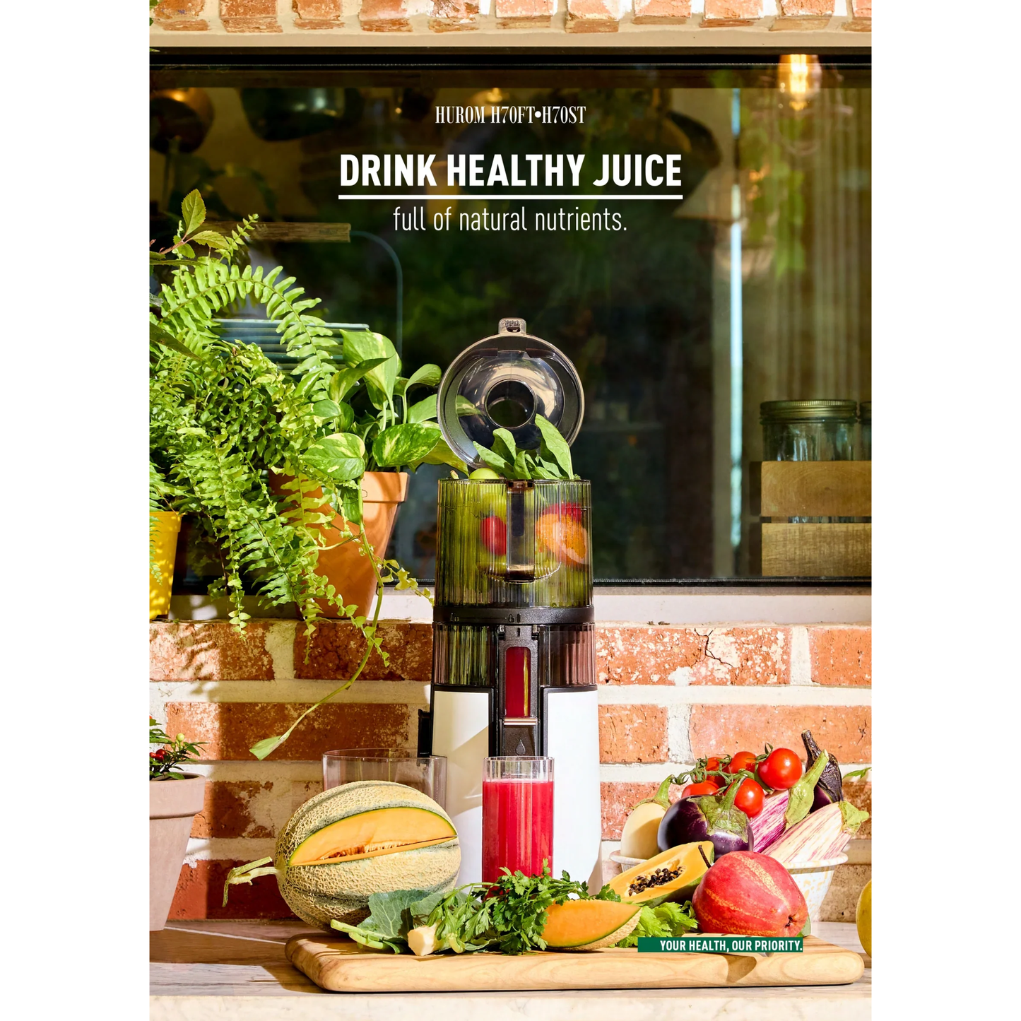 Hurom H410 Easy Series slow juicer on counter with fresh fruits, vegetables and glasses of colorful juice under slogan drink healthy juice full of natural nutrients.