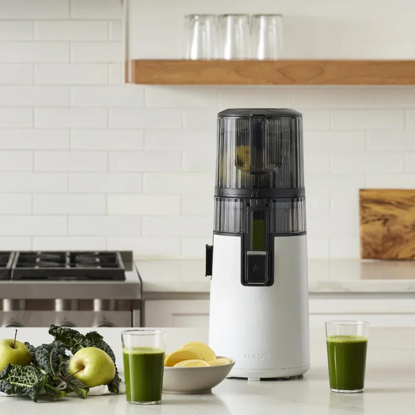 Hurom H410 Easy Series slow juicer on modern kitchen counter with fresh green juice, apples and leafy greens, showing healthy home juicing lifestyle.