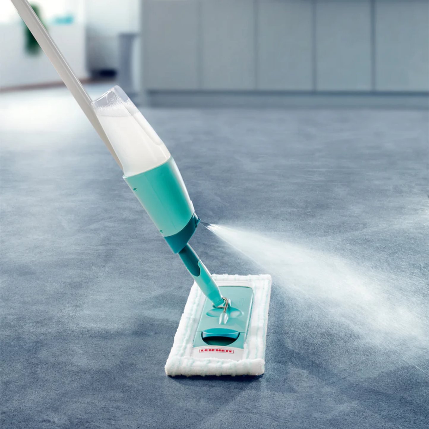 Leifheit Comfort Easy Spray XL mop spraying cleaning solution onto a tiled floor with white microfiber pad.
