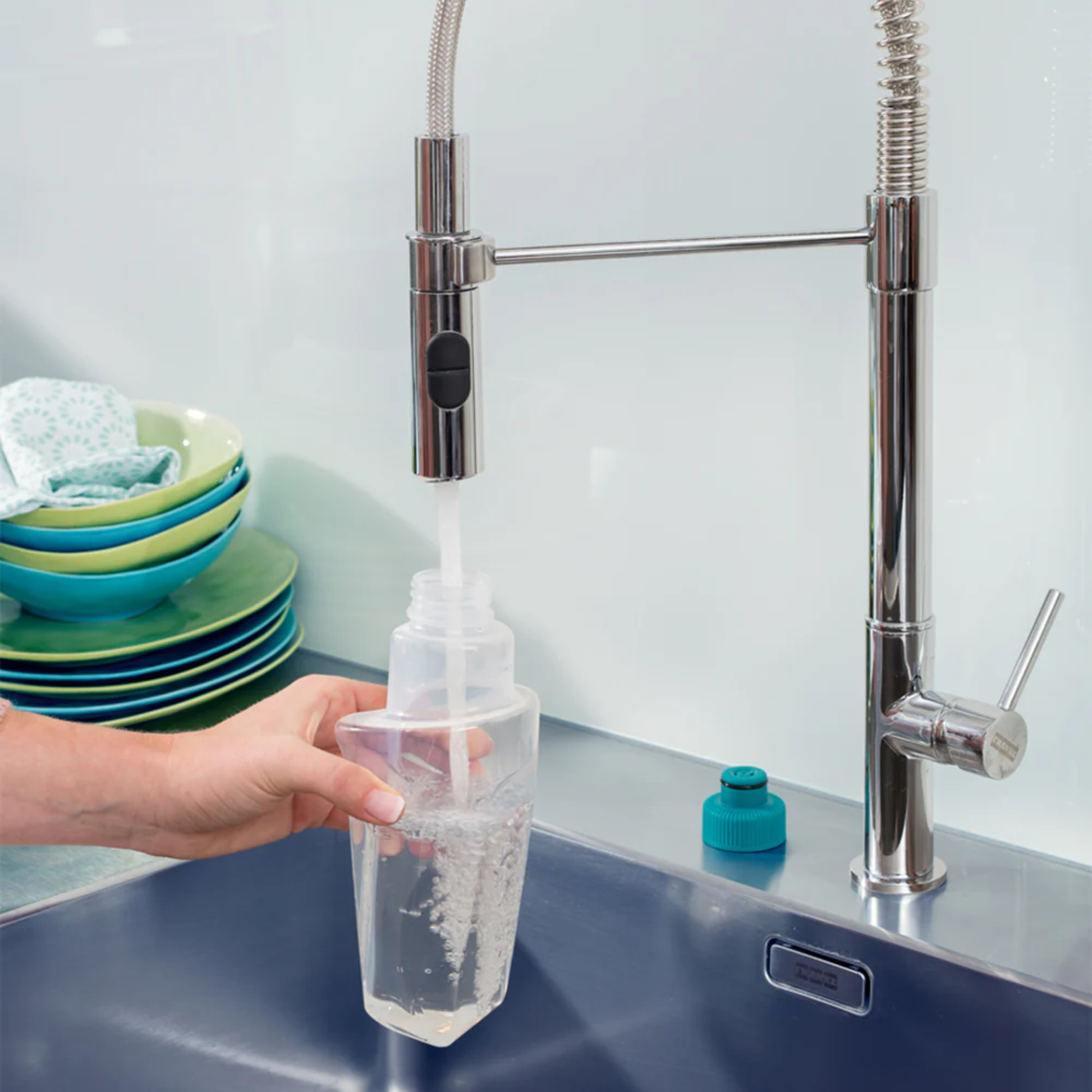Person rinsing and filling a refillable Leifheit spray mop cartridge with water at a modern kitchen sink.