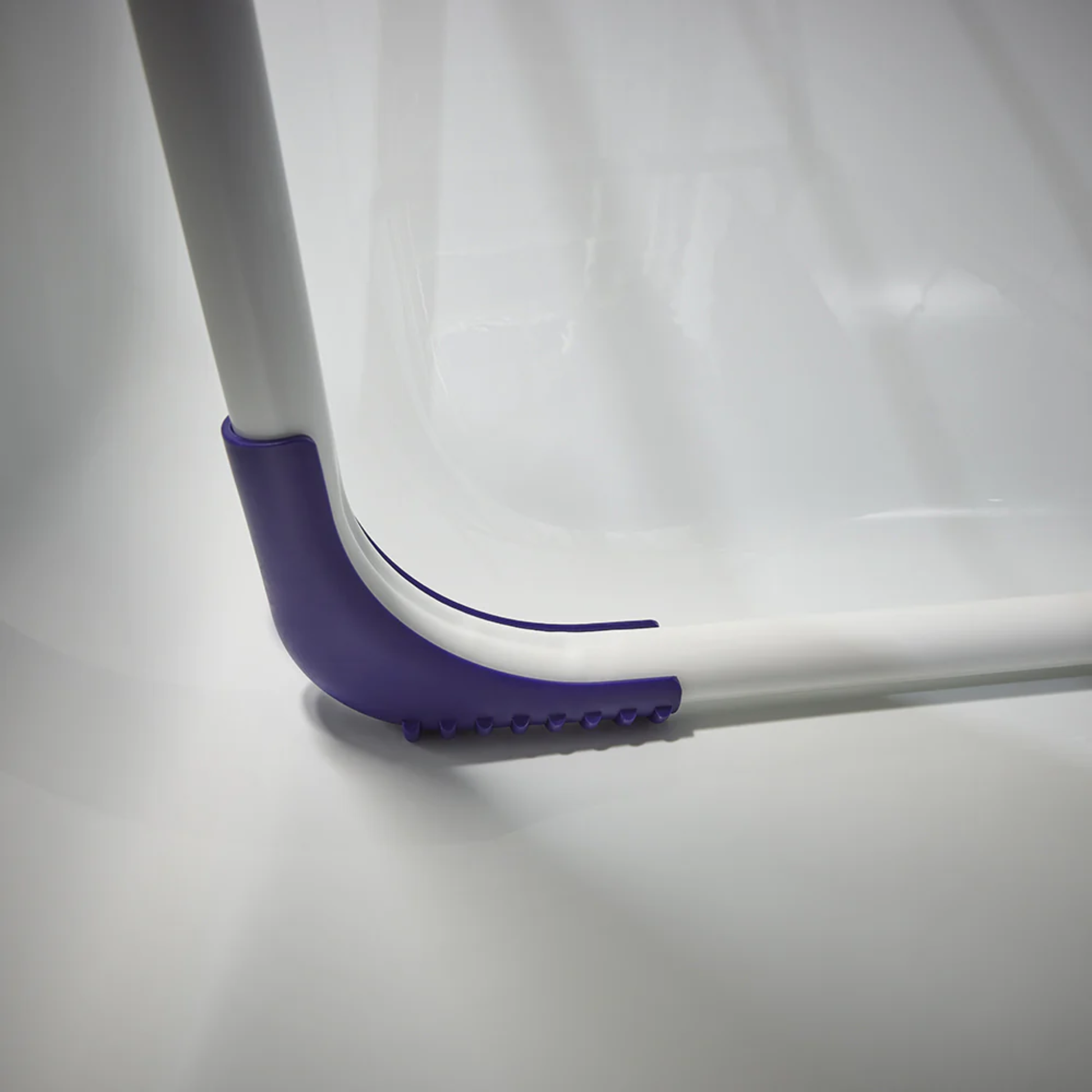 Close-up of Leifheit Pegasus 120 Solid Compact clothes drying rack with purple anti-slip feet resting securely on a bathtub surface