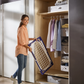 Woman storing folded Leifheit Pegasus 120 Solid Compact clothes drying rack neatly inside a wardrobe to show compact storage
