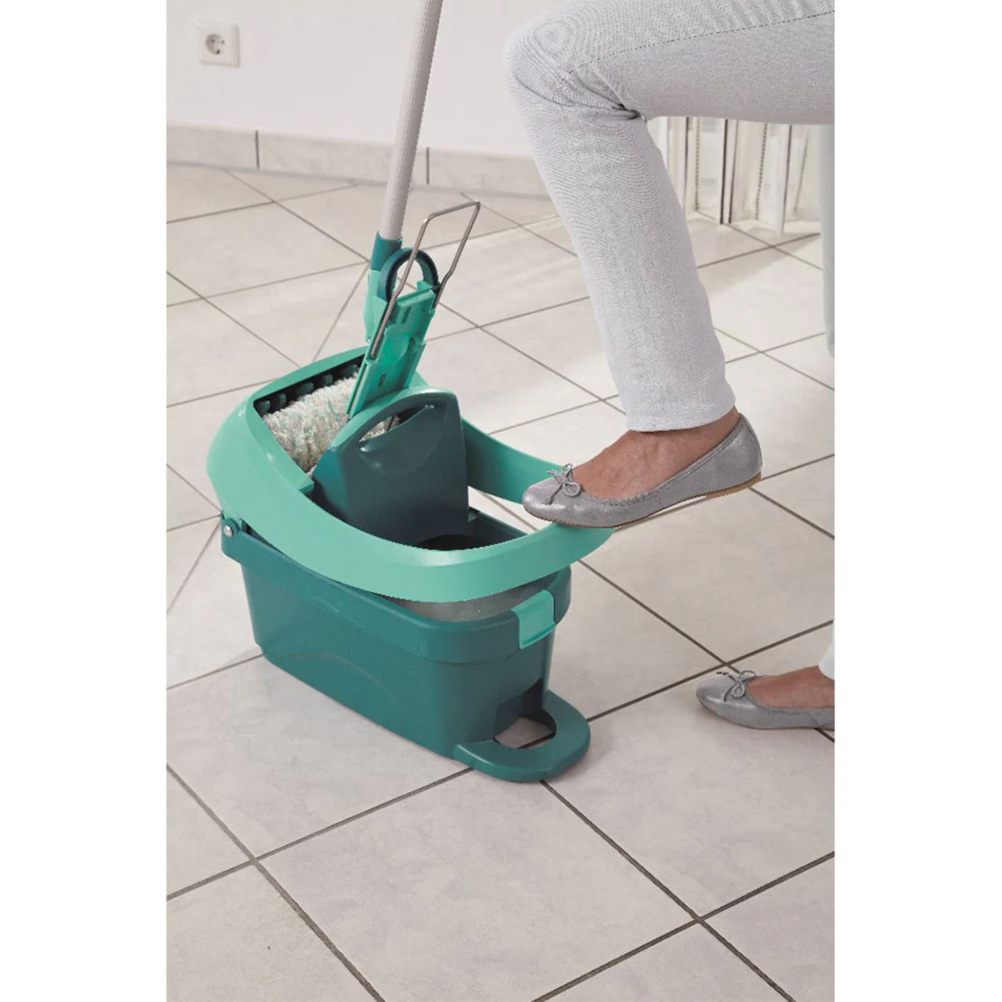 Person pressing the Leifheit Profi System mop in the foot-pedal press bucket to wring out water without using hands.