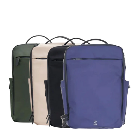 Four minimalist backpacks in green, beige, black, and blue, each with a front zipper pocket and top handle, displayed side by side on a white background