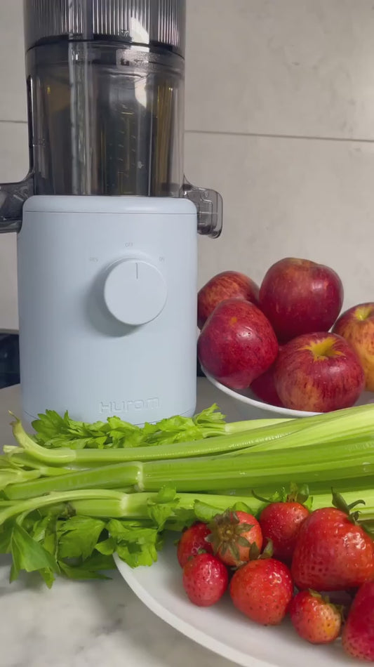 Hurom H310 slow juicer demonstrated in modern home lab, showing automatic stop safety, no-chop fruit processing, and easy cleaning design for healthy juice preparation.