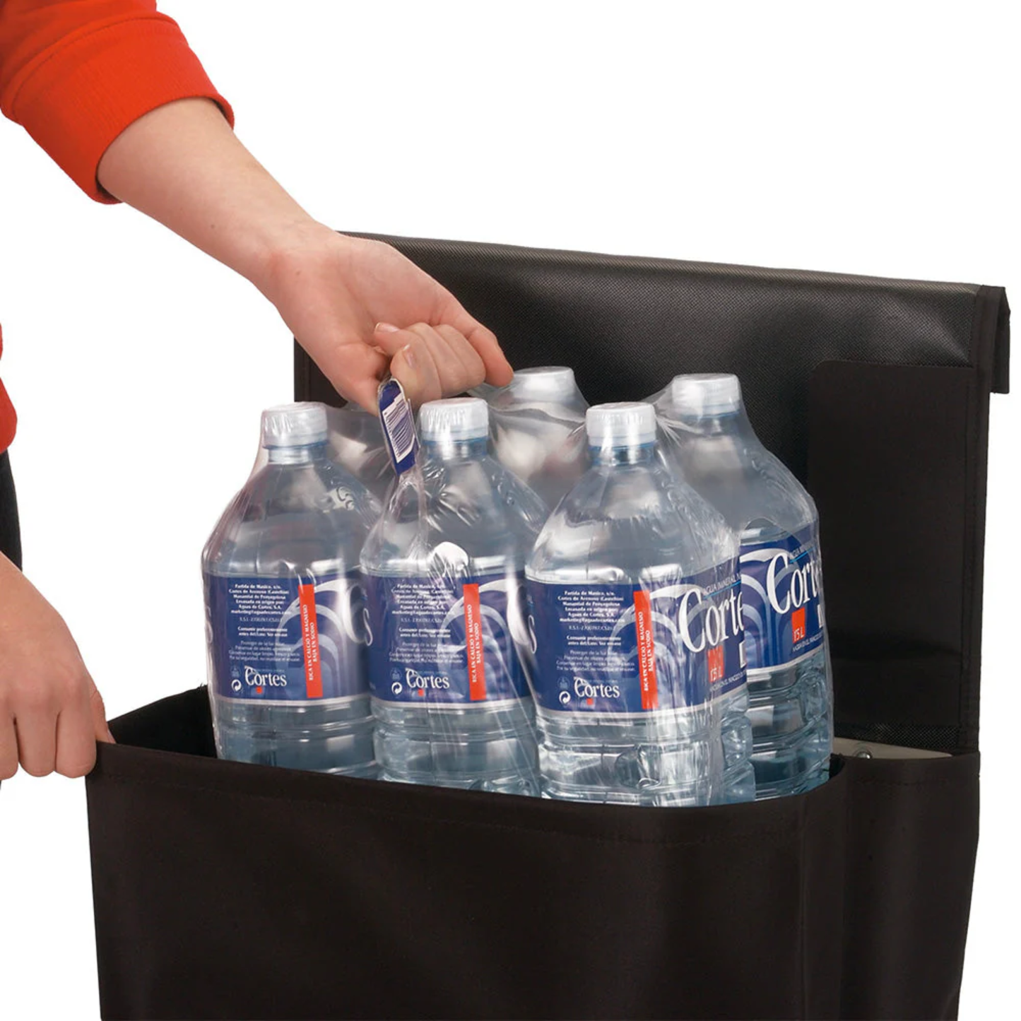 Person loading a multi-pack of large water bottles into a black Rolser Plegamatic shopping trolley, demonstrating strong weight capacity and deep bag.