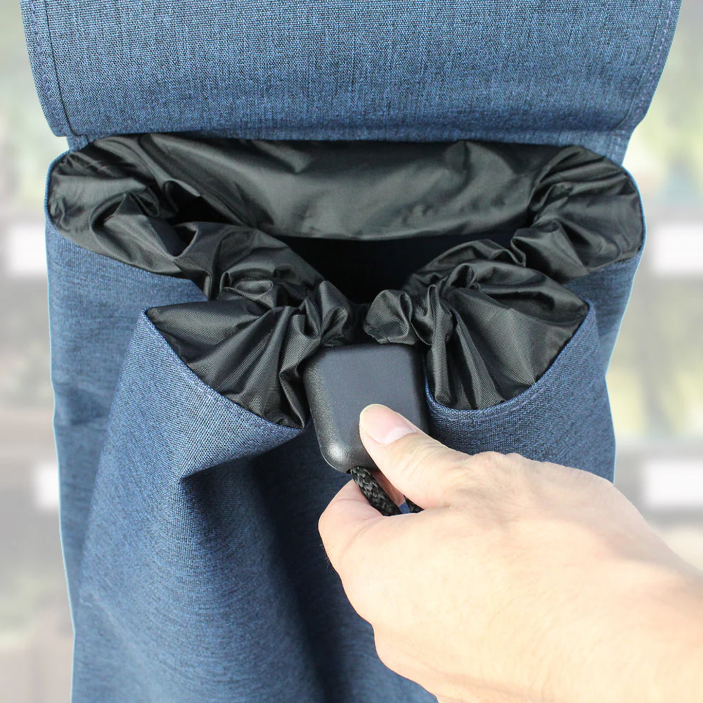 Hand tightening the drawstring closure on a blue Rolser tweed grocery shopping trolley bag, showing water-resistant inner lining close up.