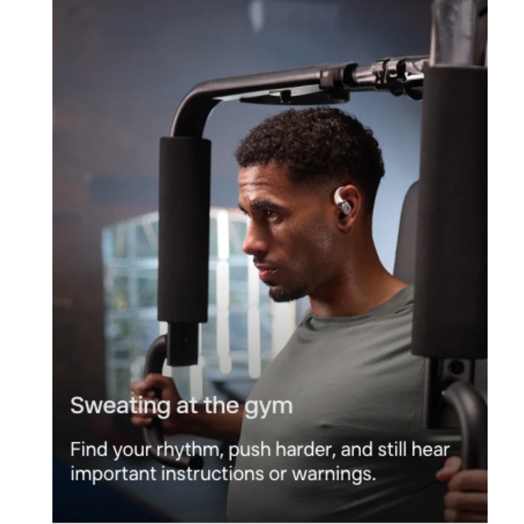 Person wearing Shokz open-ear wireless earbuds exercising on gym equipment and staying aware of surroundings