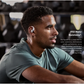 Person wearing Shokz OpenFit 2+ wireless earbuds at the gym, highlighting IP55 water resistance for sweat and rain