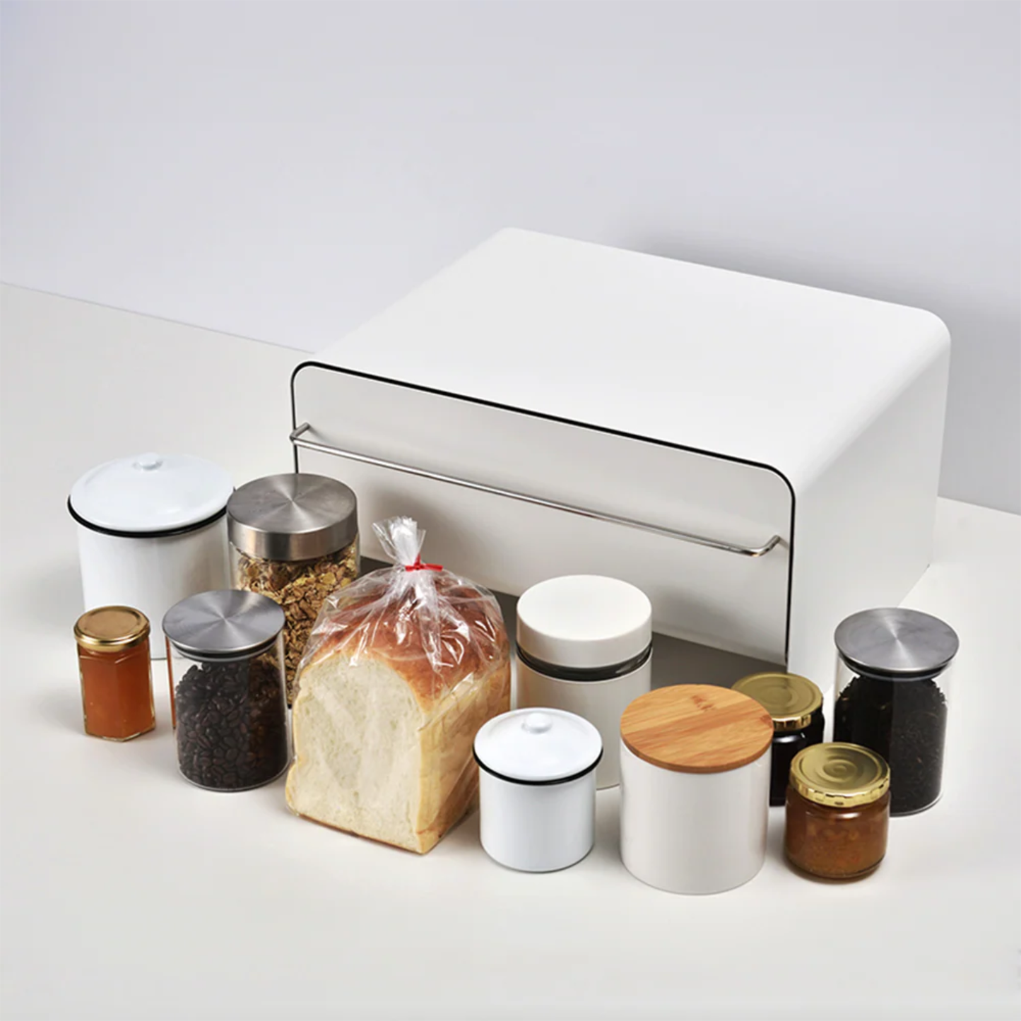 UtaU Bread Drawer in white on countertop, surrounded by bread loaf, cereals, coffee beans and condiment jars to show kitchen storage capacity.