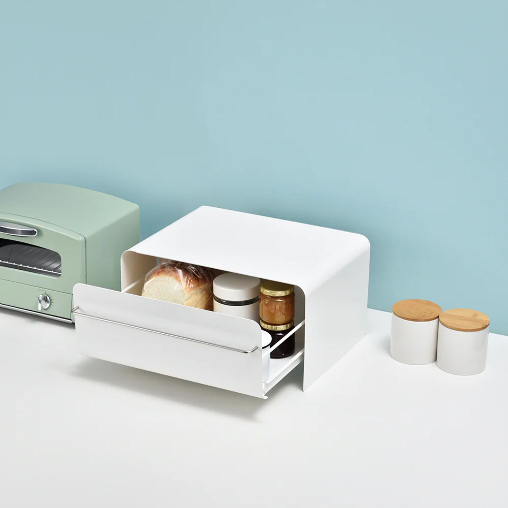 UtaU Bread Drawer in white on minimalist kitchen counter, open to show stored bread and jars beside retro toaster and condiment canisters